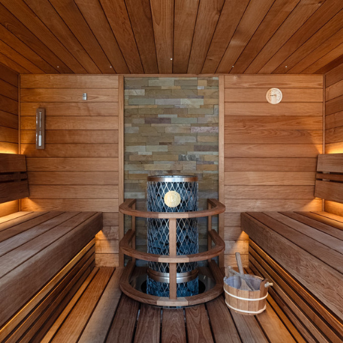 Wooden sauna with a central water tank and benches.