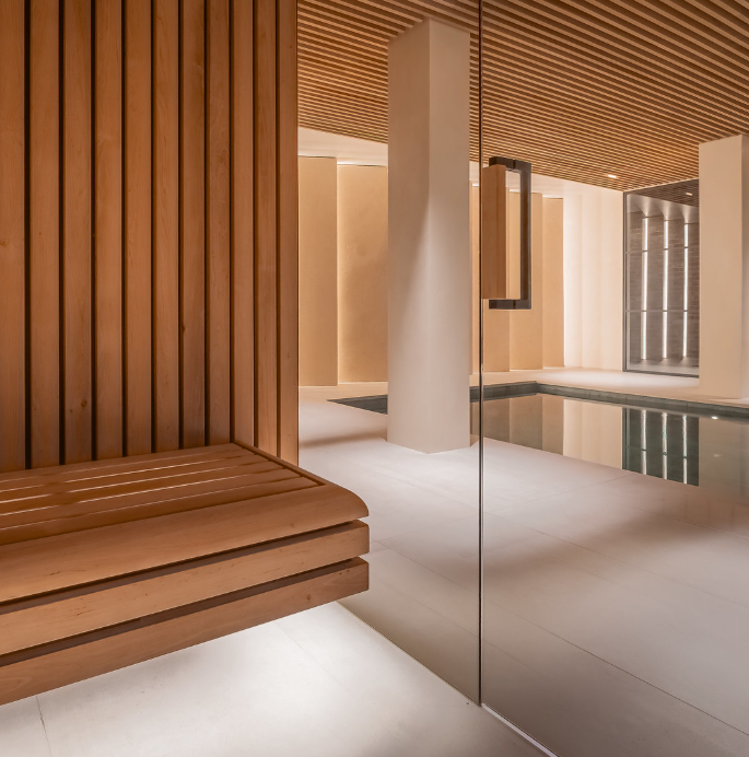 Modern indoor pool area with wooden bench and glass wall