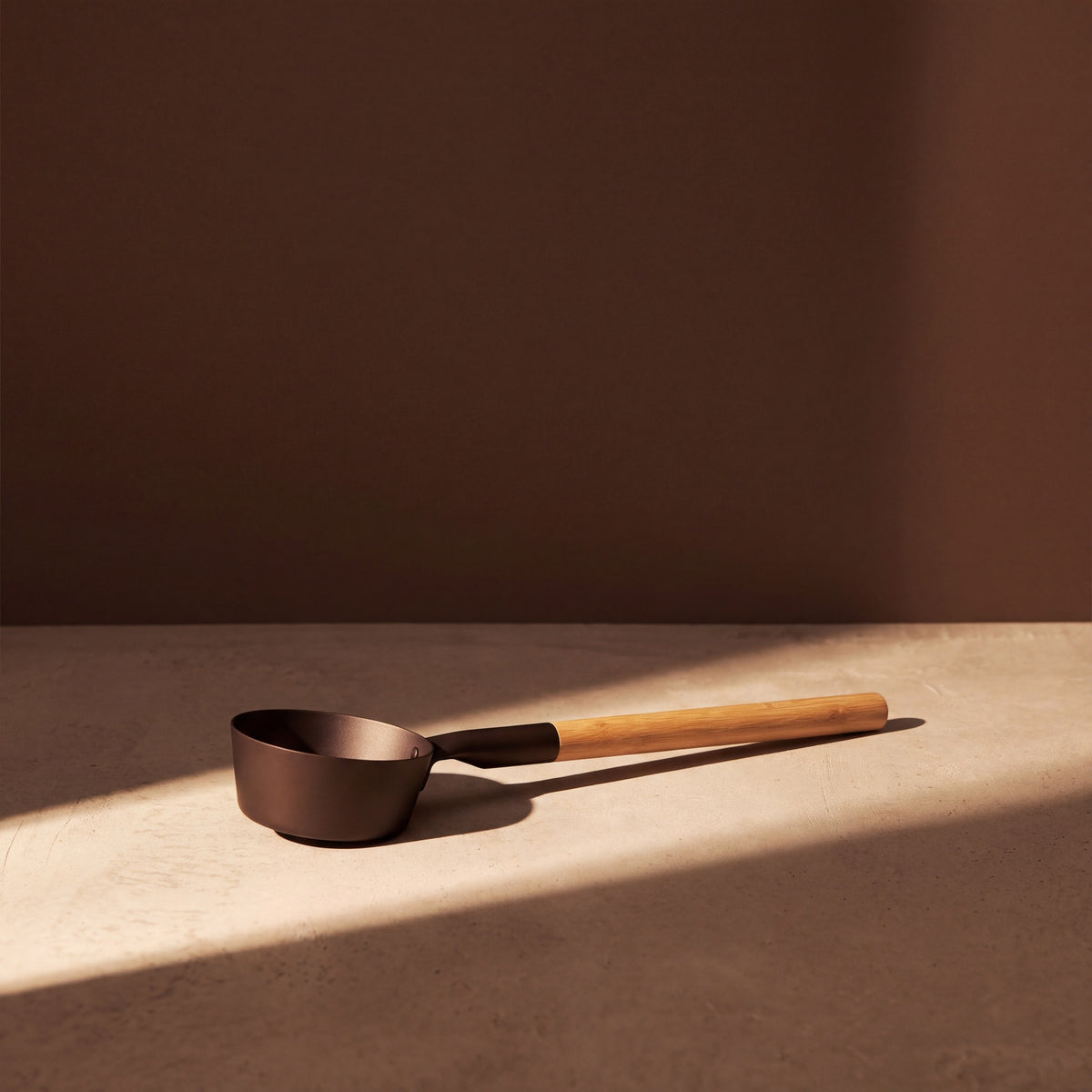 Rento Anodised Aluminium Sauna Ladle in Brown/Black - lifestyle in sunlight