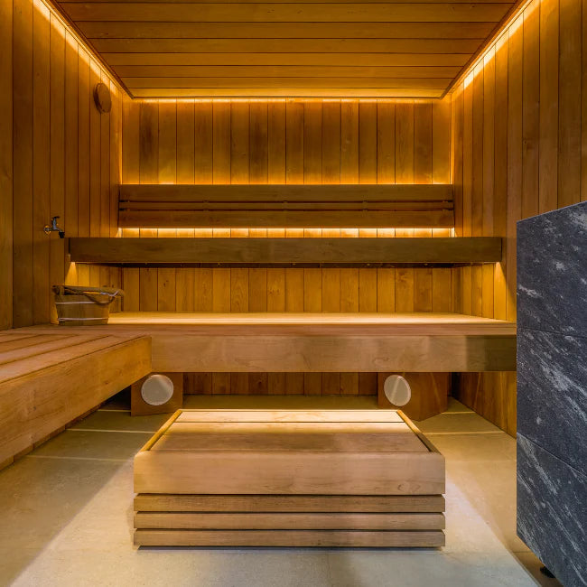 Wooden sauna interior with benches and a stone wall.