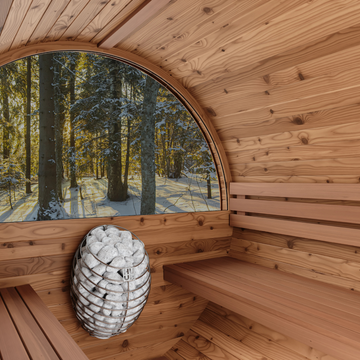 Wooden sauna interior with a view of a snowy forest outside.
