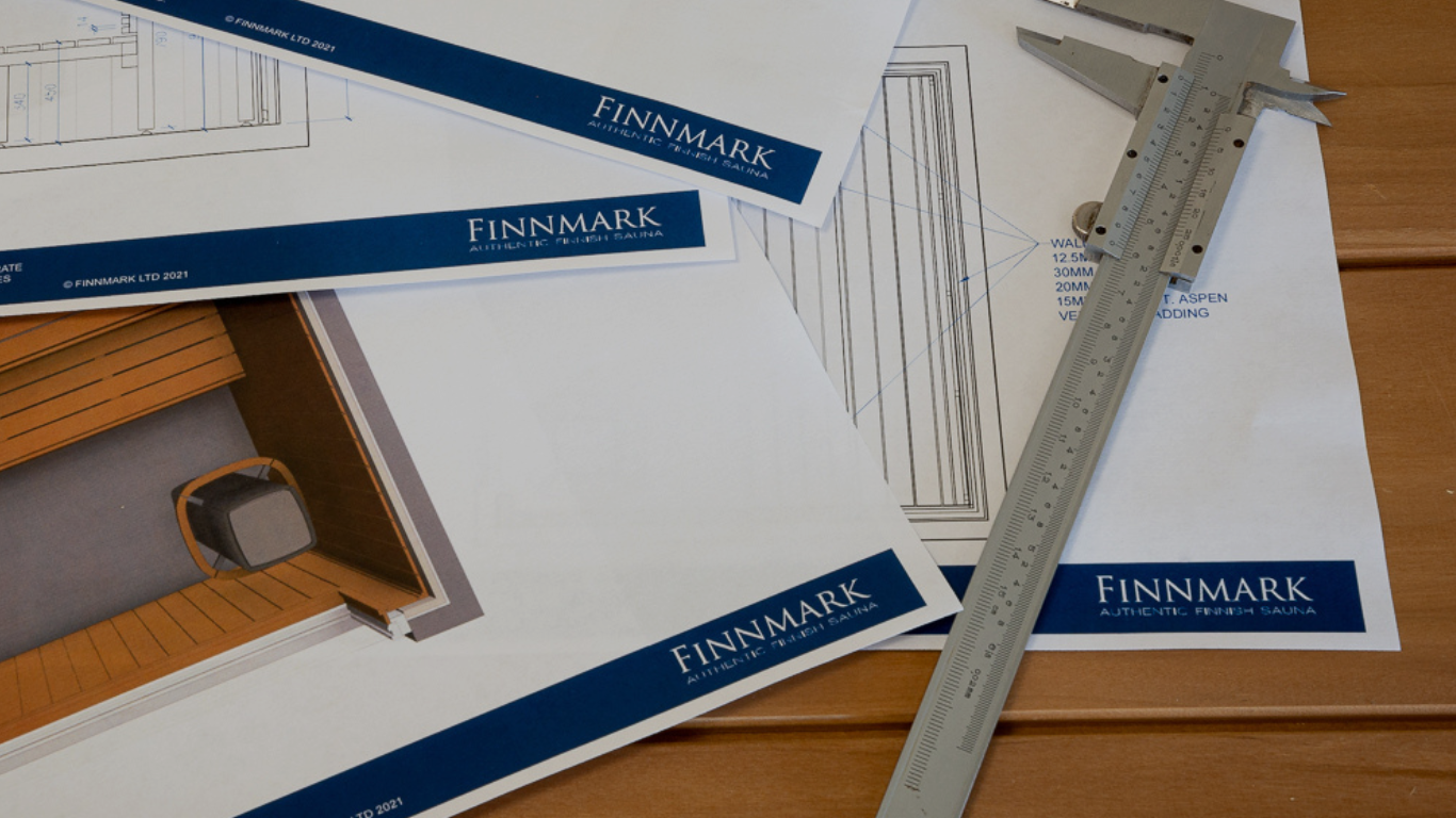 Technical drawings and measurement tools on a wooden surface with 'Finnmark' branding.