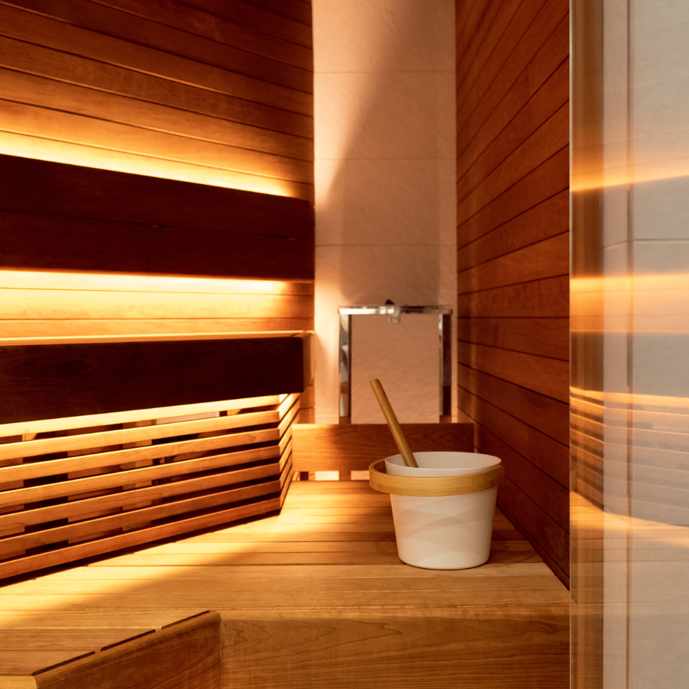 Wooden sauna interior with a bench and bucket.