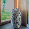 Decorative vase filled with stones next to a painting of a tree