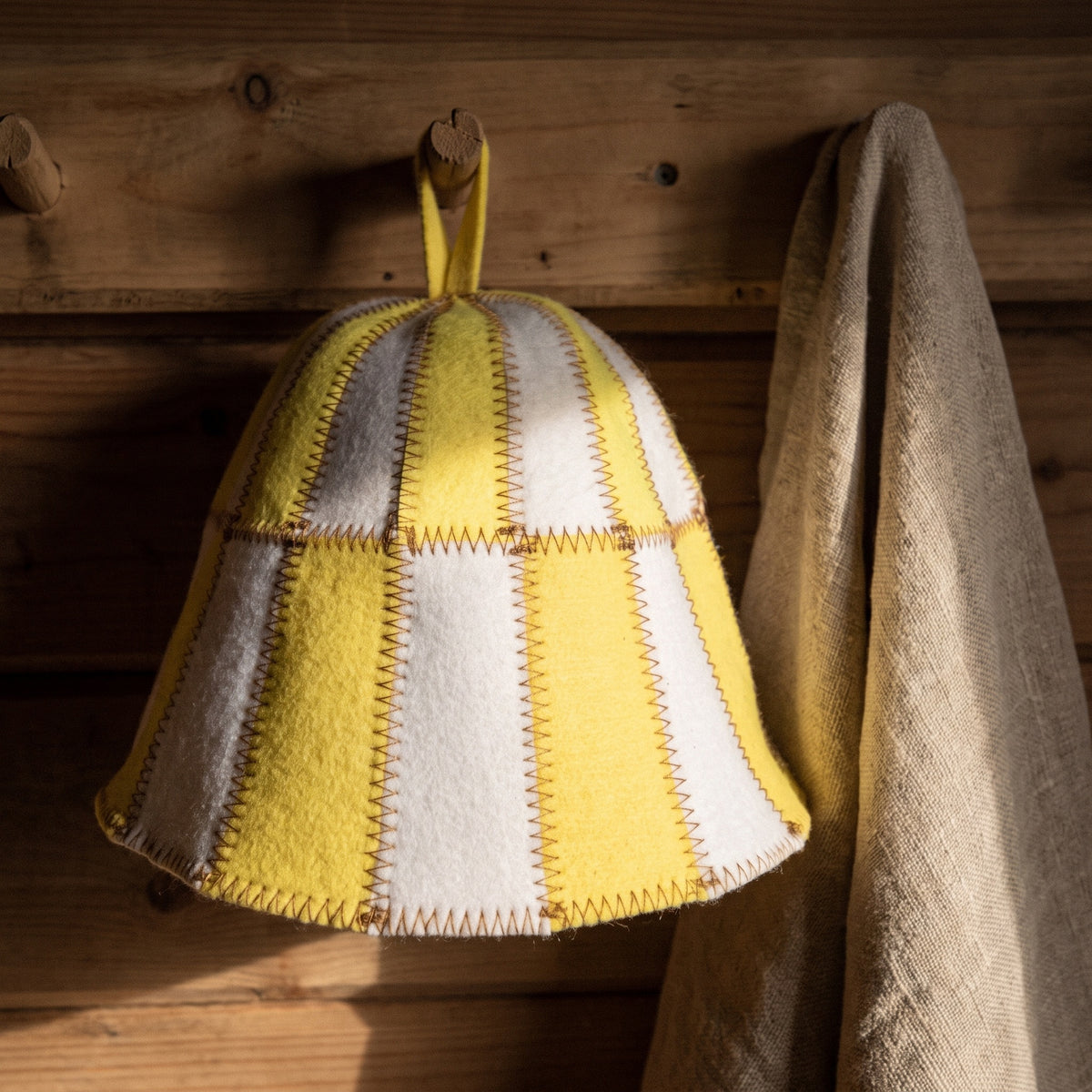 Sauna Hat Yellow/White (Polyester Felt) - hanging on a sauna peg