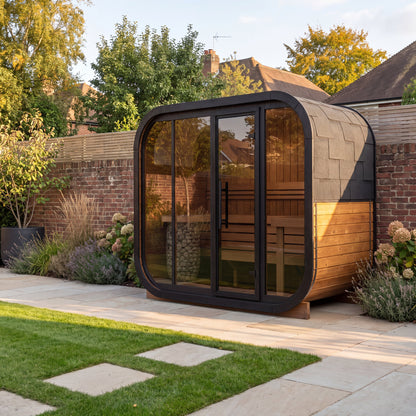 Ralva Large rounded outdoor sauna on a paved terrace beside a lawn, low autumn sun on the timber cladding