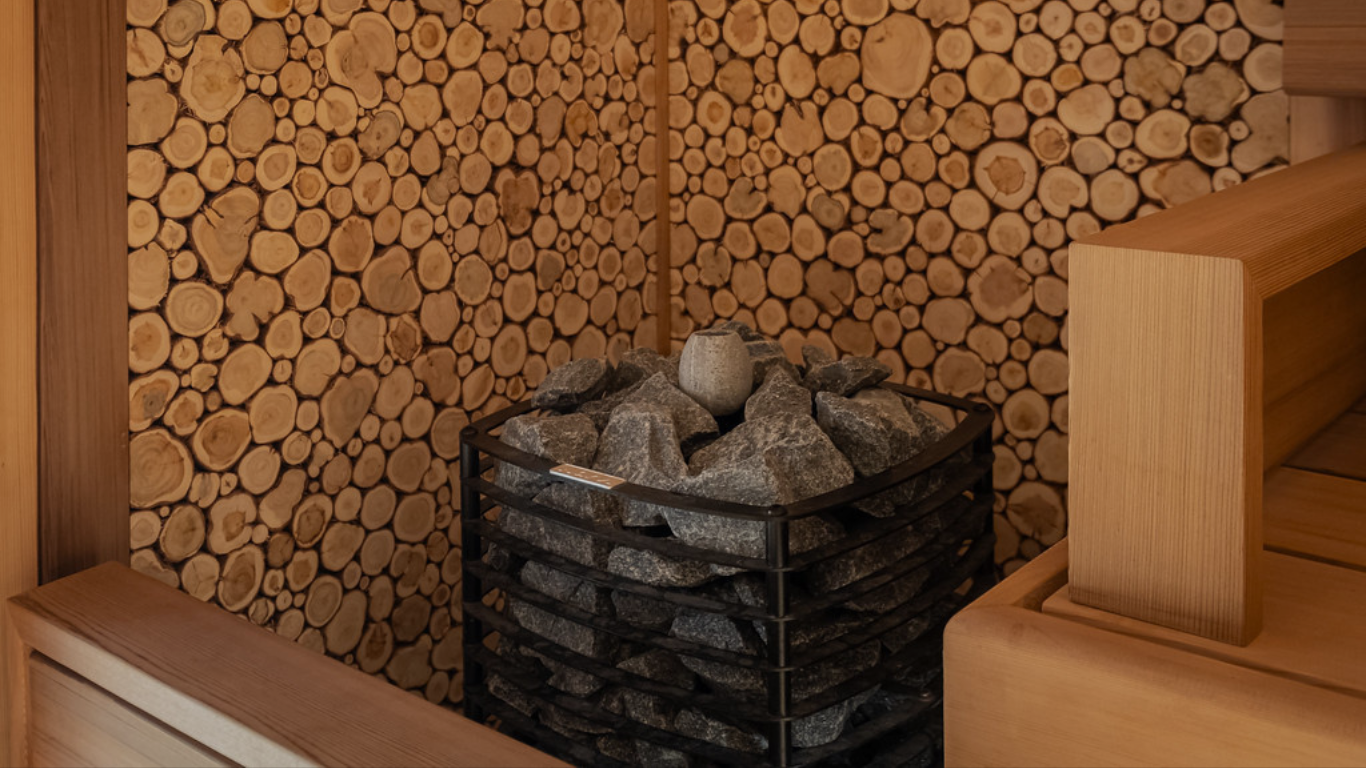 Sauna interior with wooden walls and a basket of stones.