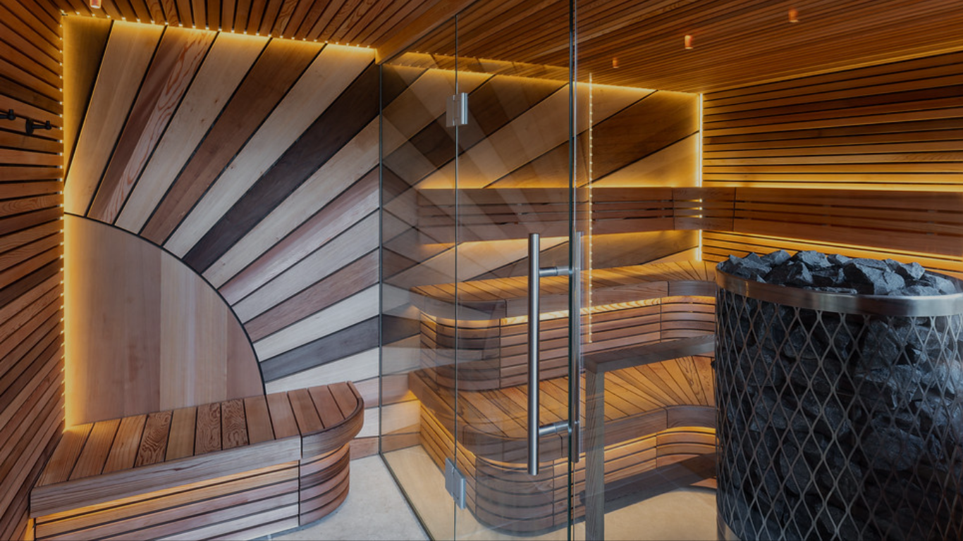 Wooden sauna interior with a glass door and stone bench.