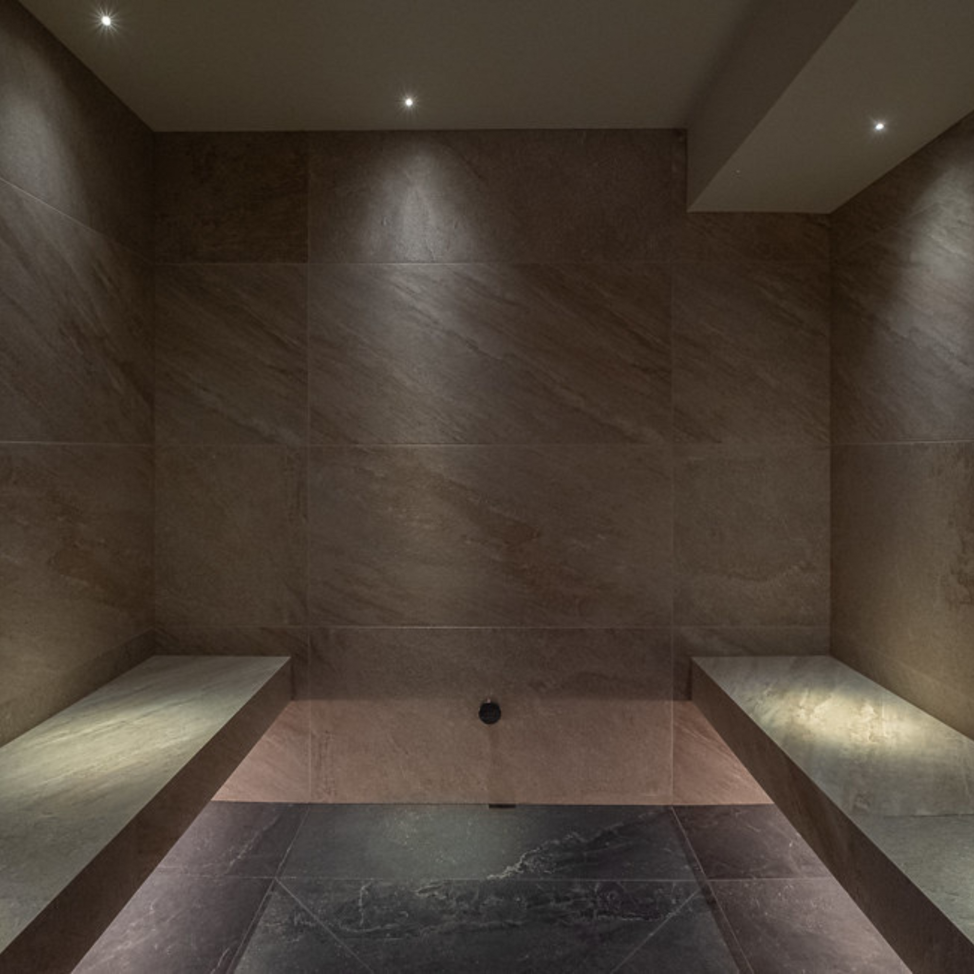 Steambath with stone walls and floor, dimly lit.
