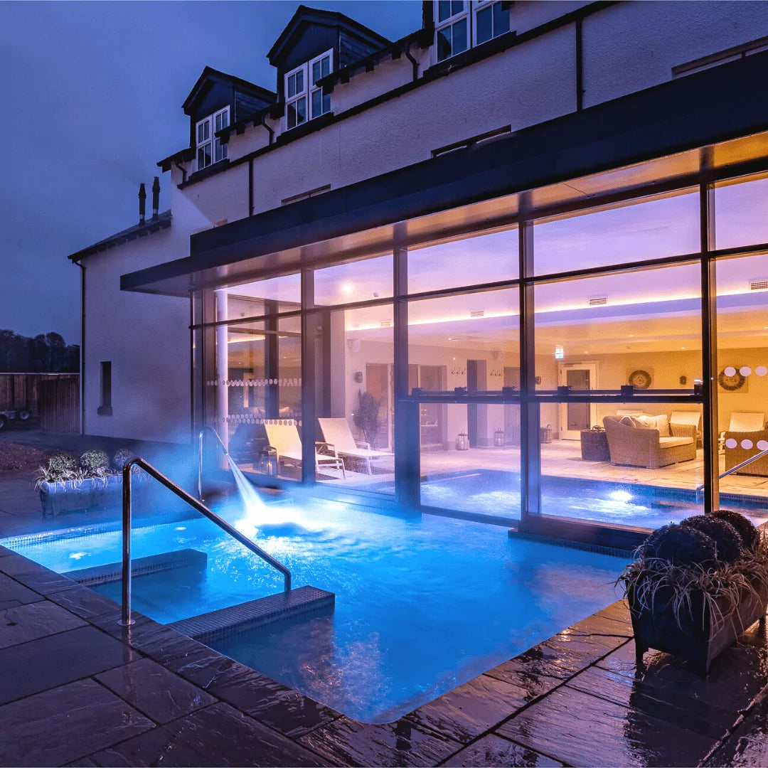 Spa with outdoor pool and indoor lounge area at night