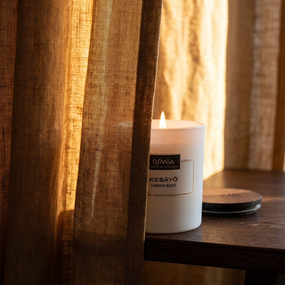 Summer Night Scented Candle by Osmia - lit behind linen curtain