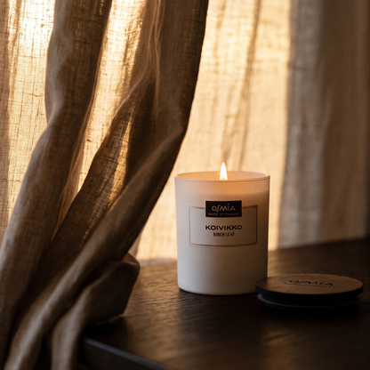 Birch Leaf Scented Candle (Koivikko) by Osmia - lit behind linen curtain