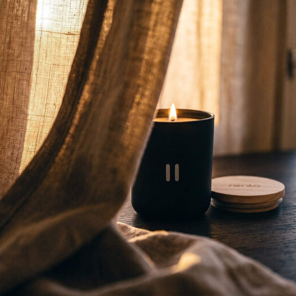 Rento Arctic Pine Scented Candle - lit behind linen curtain