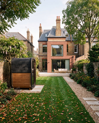 Ralva Small garden sauna with its glazed front catching evening light